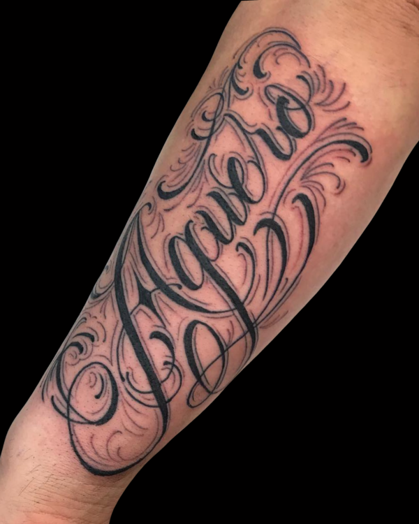Decorative script lettering tattoo on the forearm