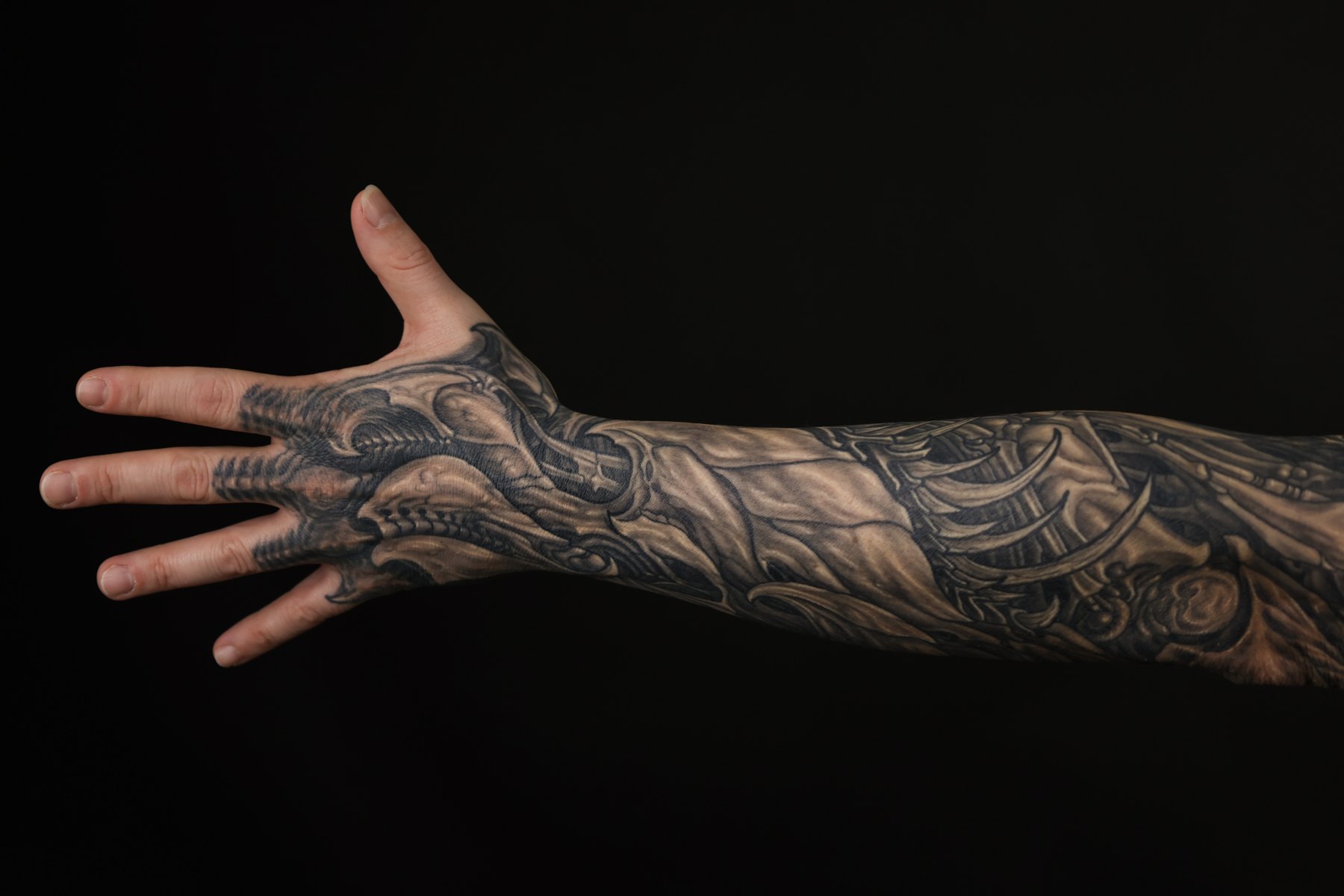 Black and grey biomechanical hand and forearm tattoo by Josh Standley