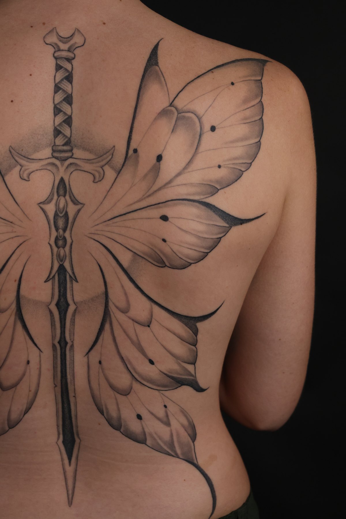 Fine line butterfly wing and sword tattoo detail